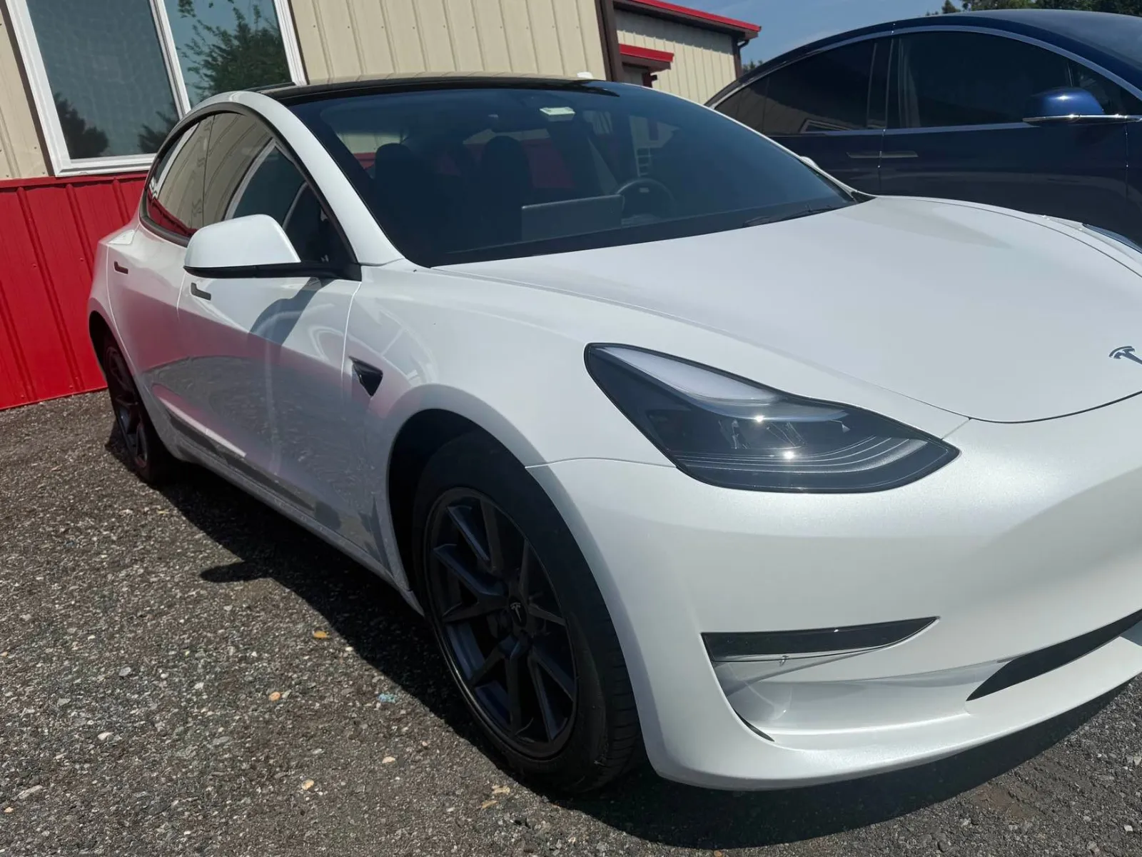 White Tesla sedan after repair, front bumper and fender restored