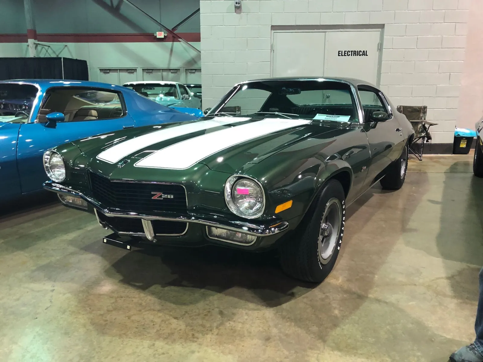 Restored dark green Camaro Z28 with white stripes at a car show