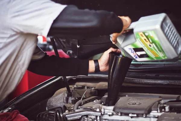 Technician pouring fresh oil into an engine during an oil change