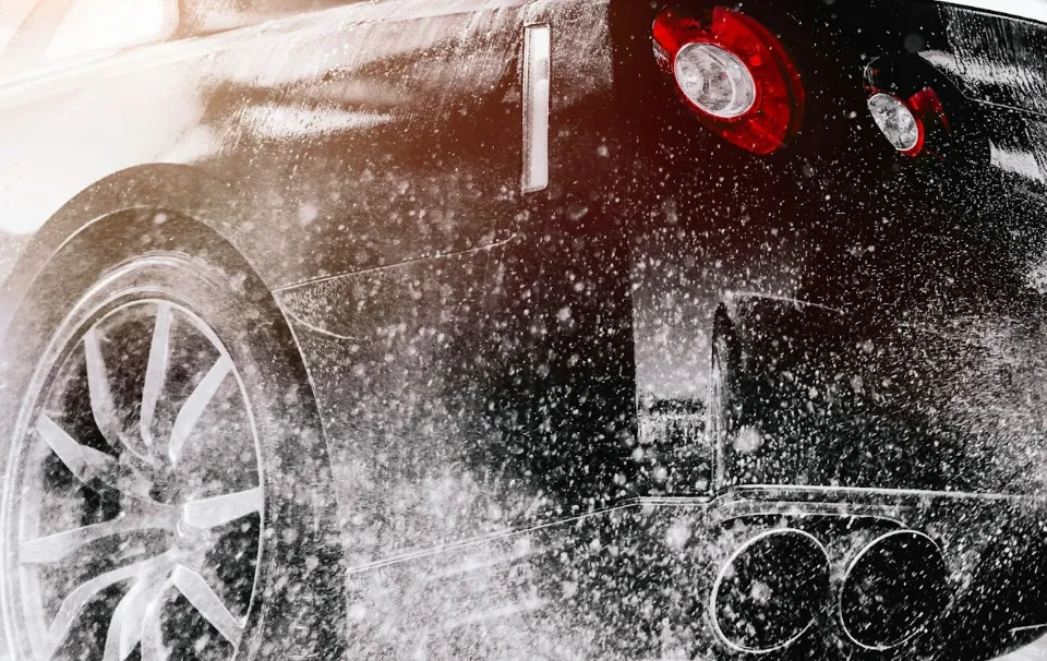 Pressure-washing the rear of a black sports car