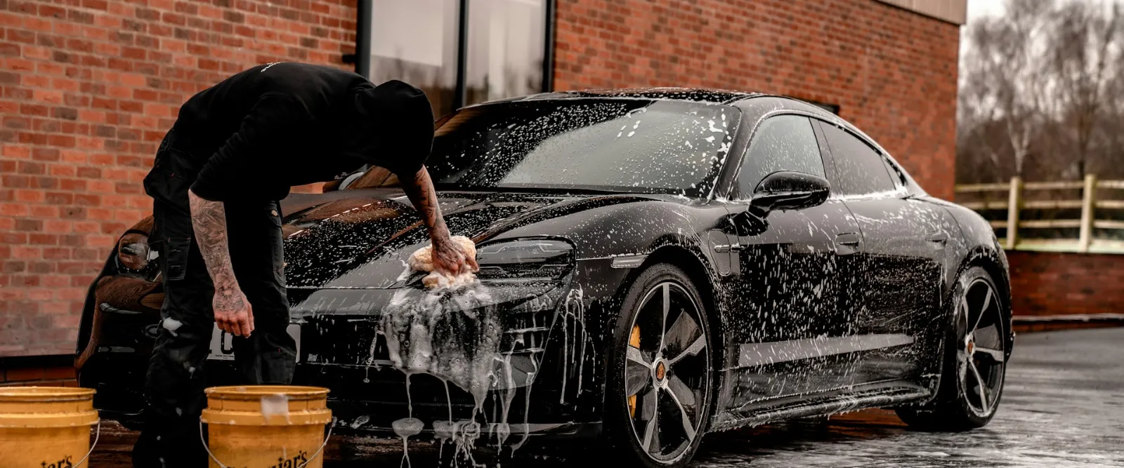 Detailer hand-washing a black Porsche Taycan